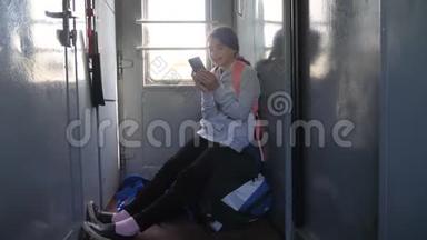 年轻的女孩旅行者带着一个背包，坐在装有智能手机的车窗上的背包上。 <strong>旅游线路</strong>
